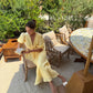 Woman wearing a butter yellow linen bias-cut skirt with a tie front linen top.