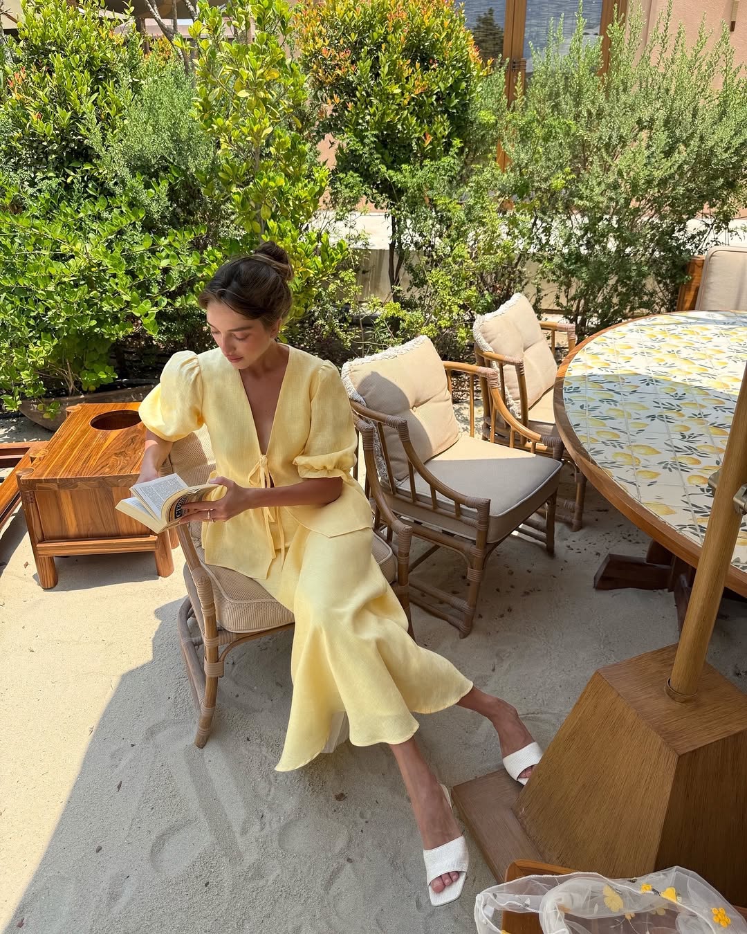 Woman wearing a butter yellow linen bias-cut skirt with a tie front linen top.