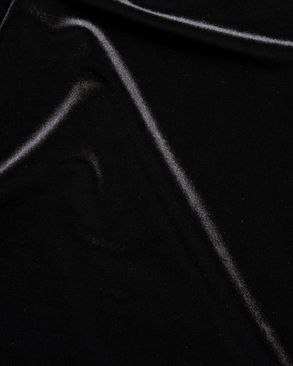 Close-up of black velvet fabric arranged in soft folds, showing its smooth surface and subtle sheen.