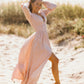 A woman in a deep neck linen long sleeve maxi dress, standing on a beach