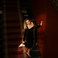 Woman walking down a staircase in a brown velvet midi dress, showing the movement of the flared skirt.