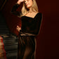 Woman in a brown velvet midi dress standing with one arm raised, showing the square neckline and fitted bodice.