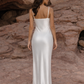 Woman in a white silk slip dress standing on rocky terrain