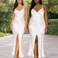 Two women standard and plus size wearing white slip dresses with high slits standing outdoors.