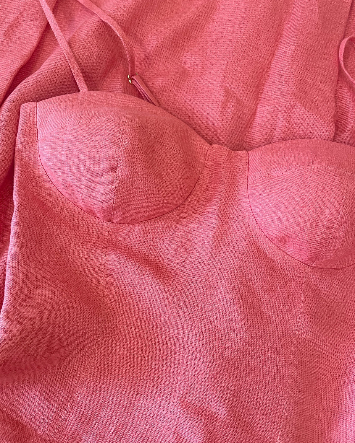 Close up of coral linen corset dress showing structured cups and natural linen texture