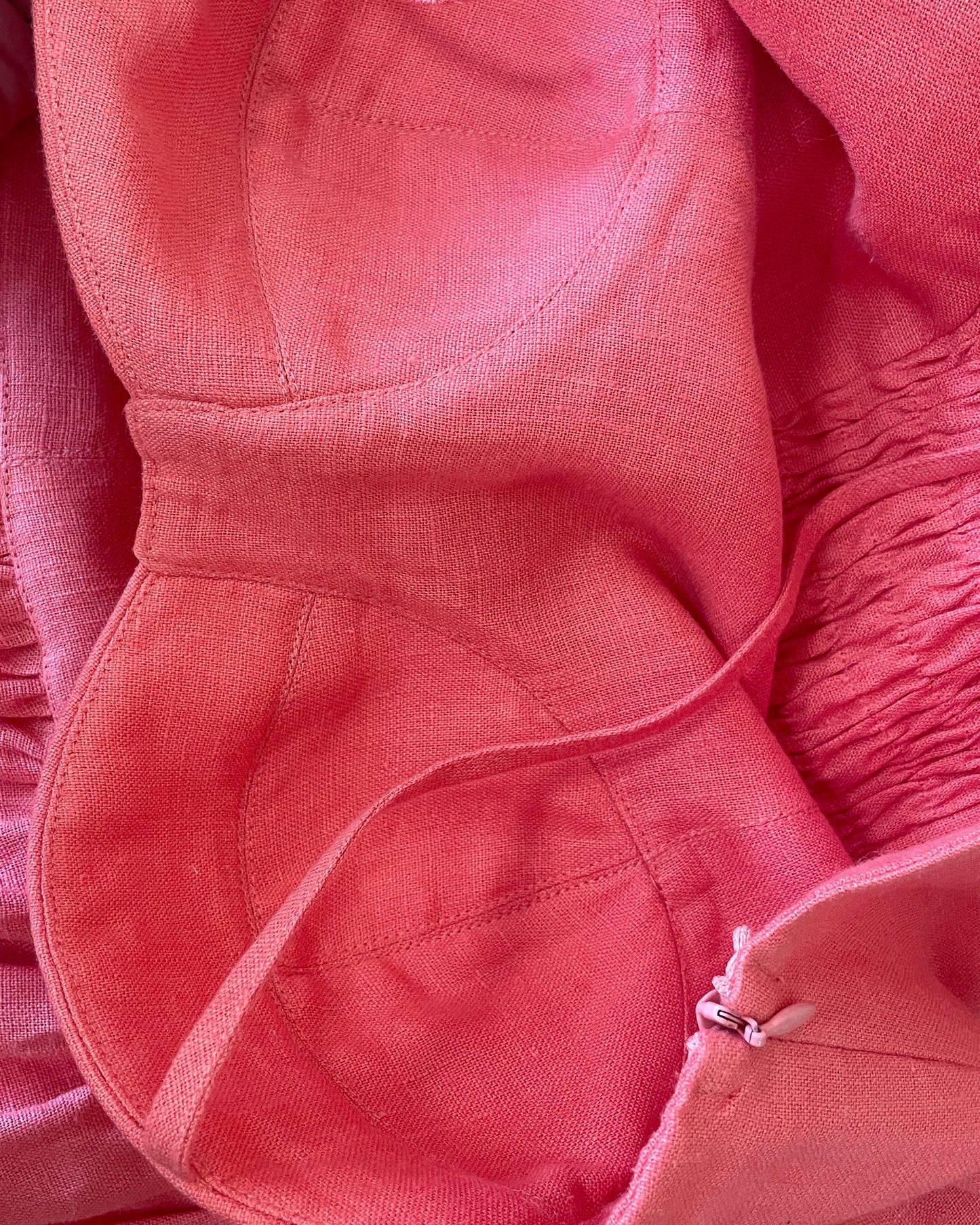 Close up of coral linen corset dress showing natural linen texture and construction details