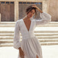 Woman in a white dress standing in front of a stone building.