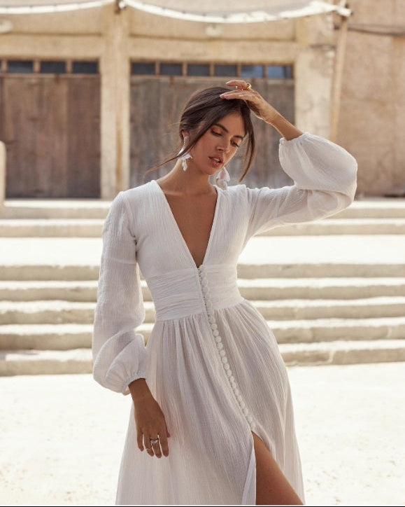 Woman in a white dress standing in front of a stone building.