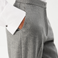 Close-up of a person wearing gray herringbone trousers with a white dress shirt and a brown leather pocket showing.