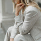 Close side view of a seated woman wearing heavyweight beige linen trousers with a matching linen blazer