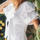 Woman wearing a white dress with ruffled sleeves in a garden setting