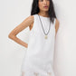 Woman wearing a white dress with lace details on a plain background