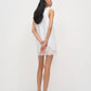 Woman wearing a white sleeveless dress with lace details on a plain background
