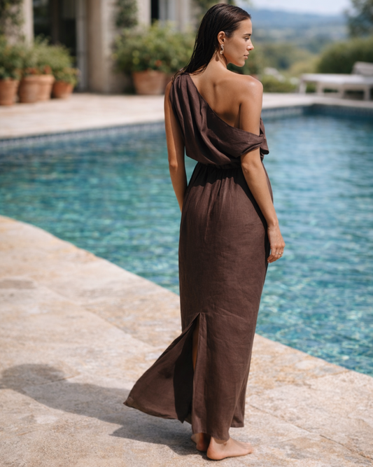 Back view of a chocolate brown one shoulder linen dress with asymmetric draped back and back slit.