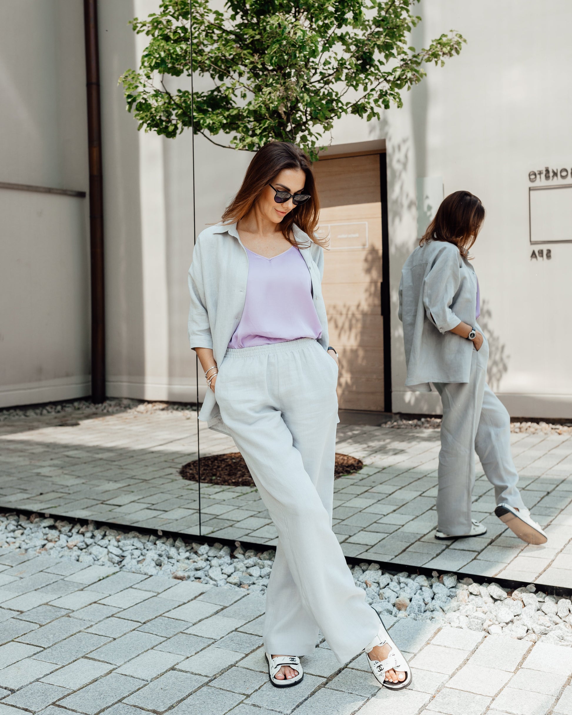 Woman wearing a grey linen two-piece set with relaxed trousers and a raglan sleeve shirt