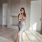 Woman in a sage slip  dress standing in a modern interior setting