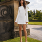 Front view of a silk mini wedding dress with flared sleeves and boat neckline.