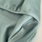 Close-up of a light green fabric with a hand holding it, on a neutral background.