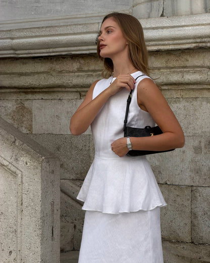 White sleeveless linen peplum top with fitted waist and feminine silhouette