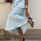 Person wearing a light blue dress with a high-low hemline, paired with dark blue high-heeled shoes.