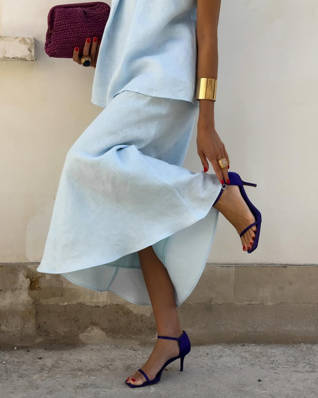 Person wearing a light blue dress with a high-low hemline, paired with dark blue high-heeled shoes.