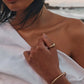 Close-up detail of a white one shoulder linen dress with soft draping, gold jewelry, and lightweight textured linen fabric.