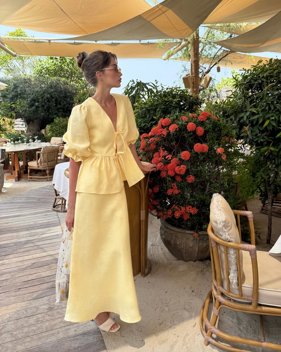 Woman wearing a butter yellow linen tie front top and bias-cut midi skirt set.