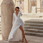 Woman in a white dress standing in a desert-like setting with architectural elements.