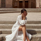 Woman in a white dress sitting on stone steps with a desert building in the background