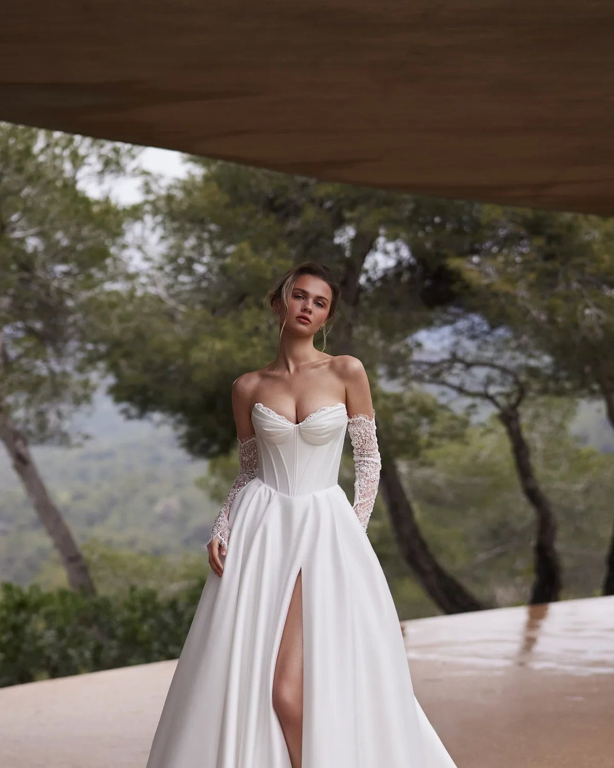 Woman in a white corset with lace  standing outdoors with trees in the background