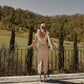 Back view of a beige linen midi dress with back slit and tie shoulder straps