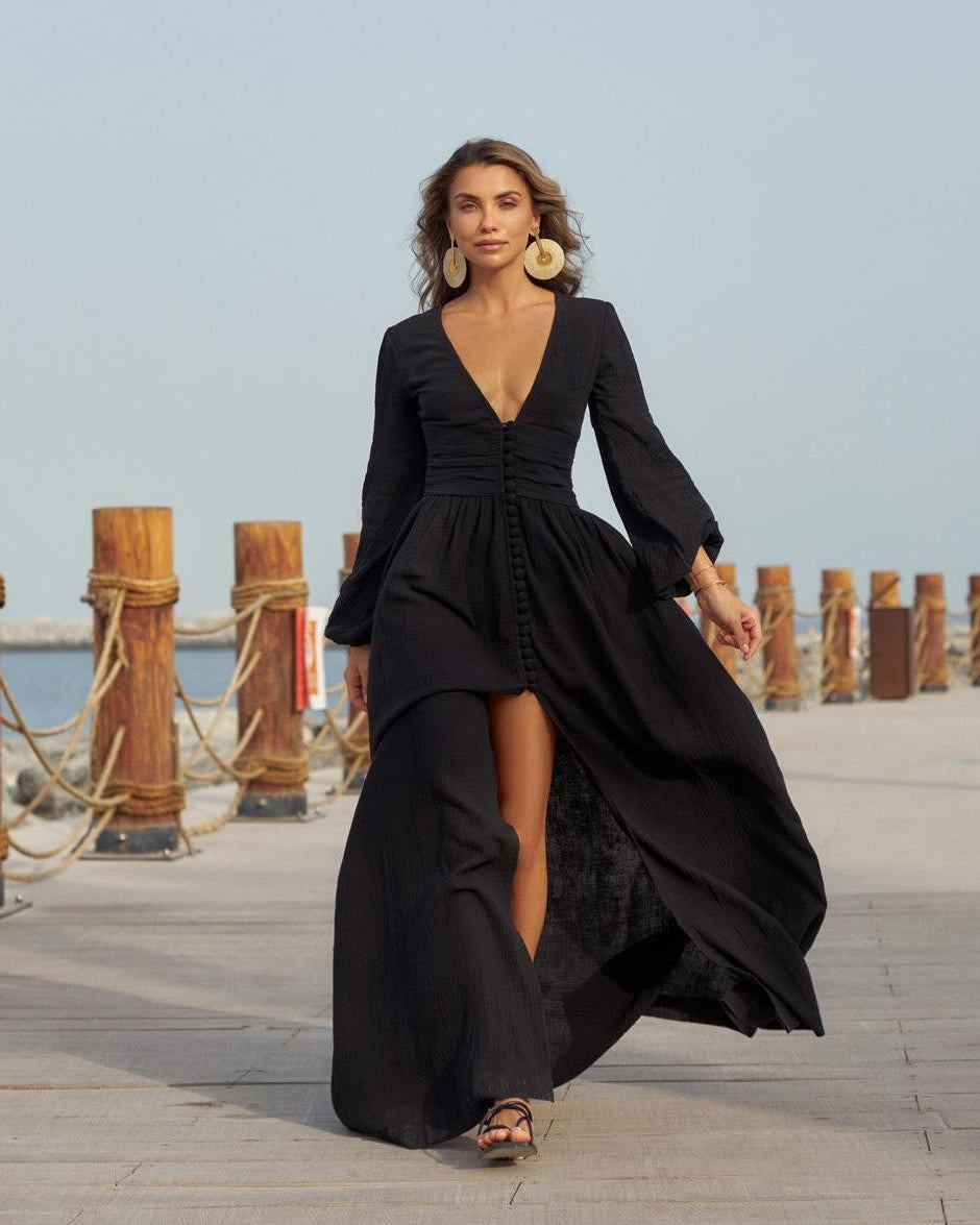 Woman wearing a black muslin maxi dress with a plunging V-neck, draped waist and adjustable button-front skirt.