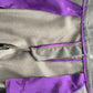 A close-up of a garment featuring a textureddark green fabric body with vibrant purple silk panels and trim, decorated with dark purple horse silhouettes.