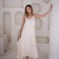Full length view of a woman wearing an ivory silk midi slip dress with thin straps and a softly flowing skirt