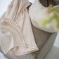 Ivory silk satin dress draped over a stone pedestal beside a white vase with flowers