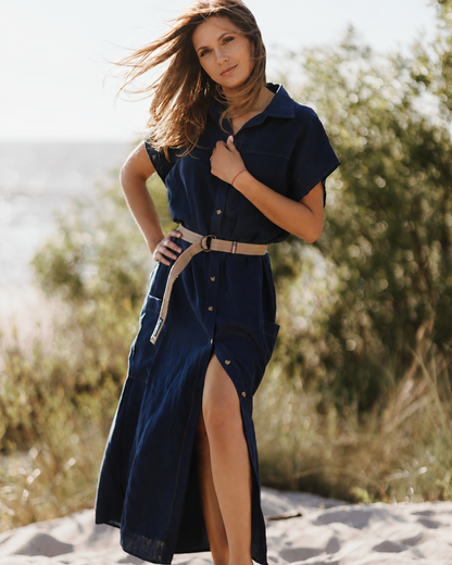 Woman wearing a navy blue dress with a slit on a sandy beach.