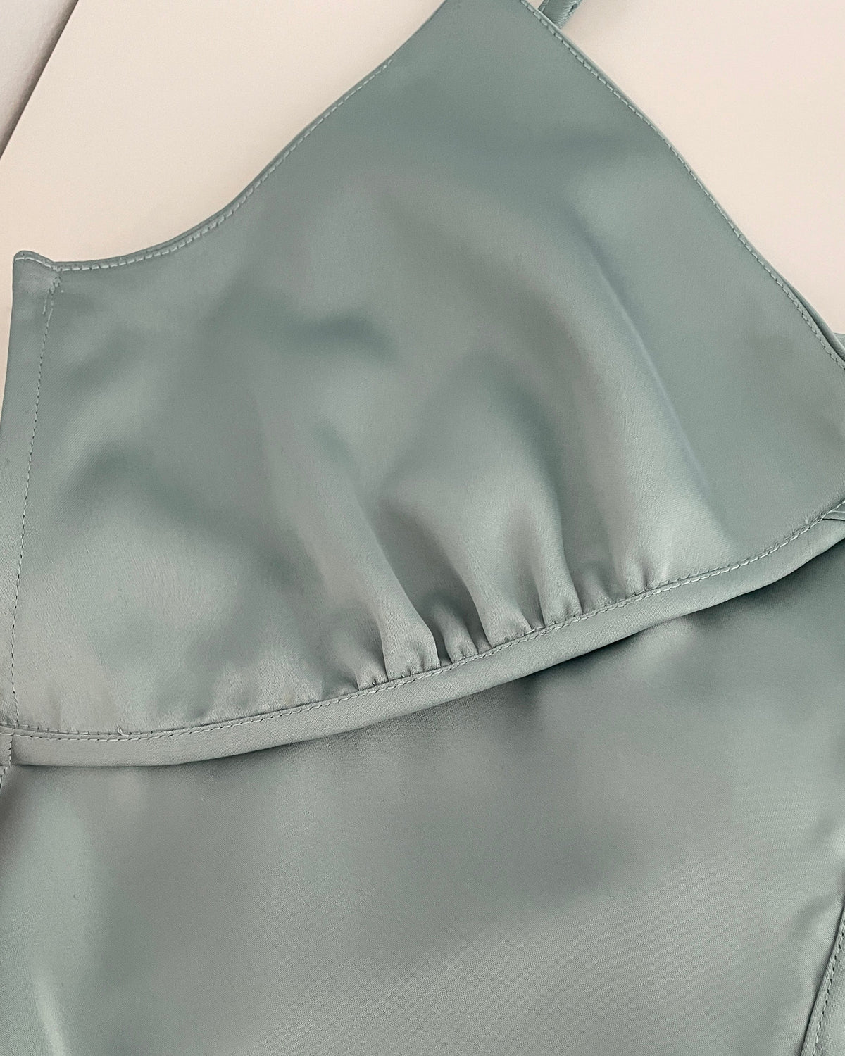 Close-up of a sage swimsuit top on a beige background