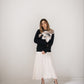 Woman wearing an ivory silk midi dress layered with a black floral sweater and black heels