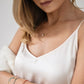 Close up of a woman wearing an ivory silk slip dress showing the V neckline and thin shoulder straps