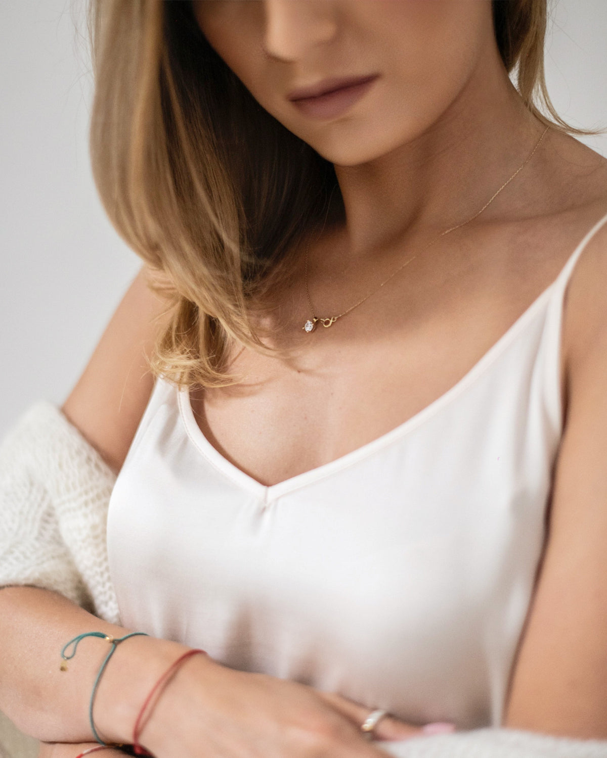 Close up of a woman wearing an ivory silk slip dress showing the V neckline and thin shoulder straps