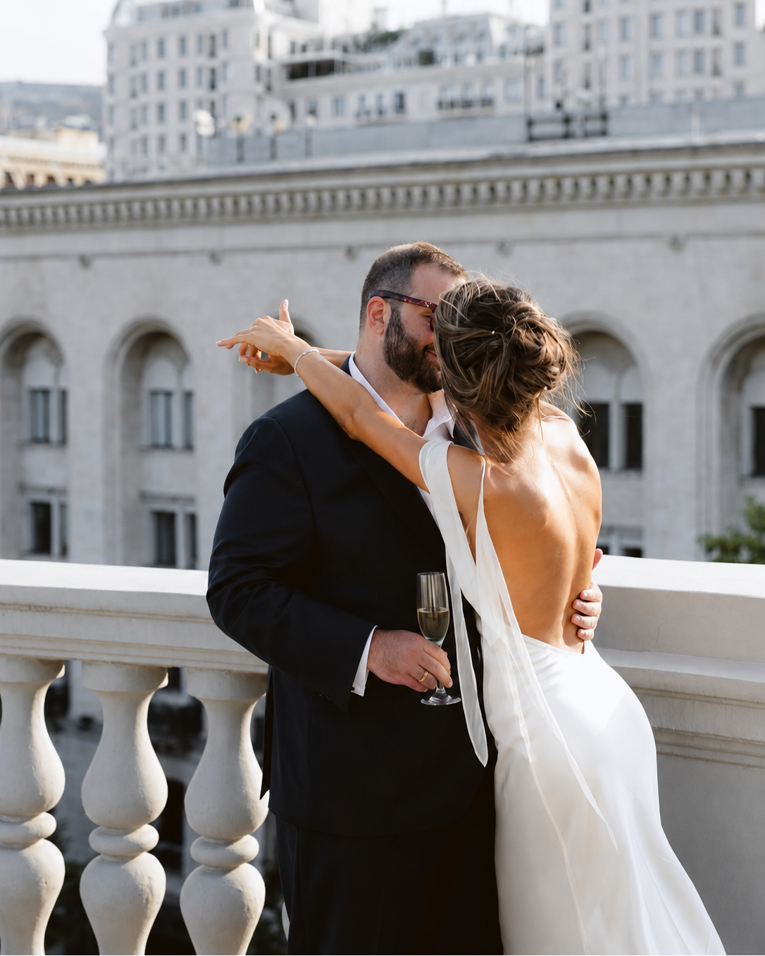 Bride wearing an ivory silk maxi dress standing with her partner.