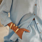 Light blue shirt with wood buttons worn by a person, with a focus on the sleeve and hand.