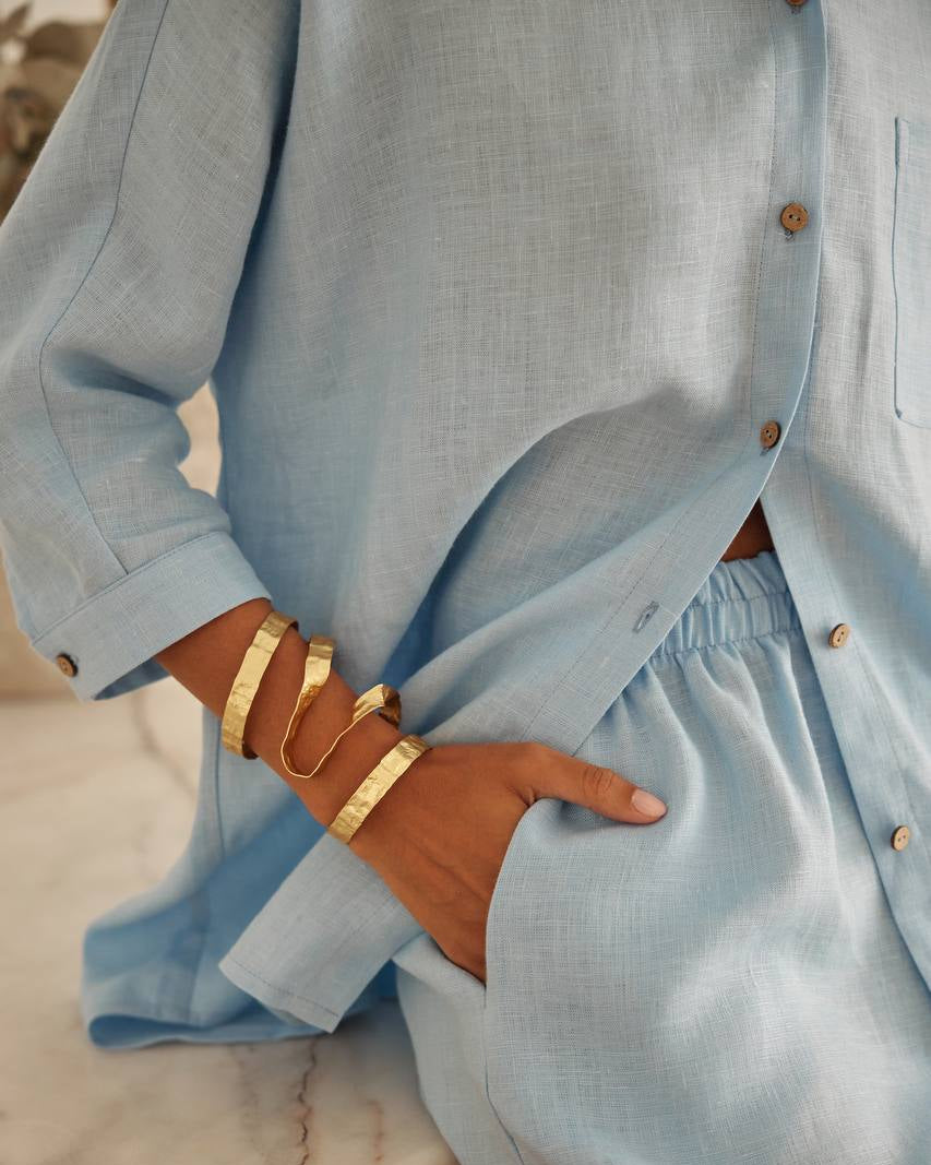 Light blue shirt with wood buttons worn by a person, with a focus on the sleeve and hand.