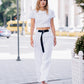 Woman walking through the city in a white linen crop top with puff sleeves, styled with white wide-leg trousers and a black belt.