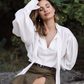Woman wearing a white ascot tie-neck blouse with shoulder draping, voluminous sleeves and long structured cuffs.