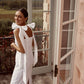 Back view of a white linen midi dress with oversized tie shoulder bows