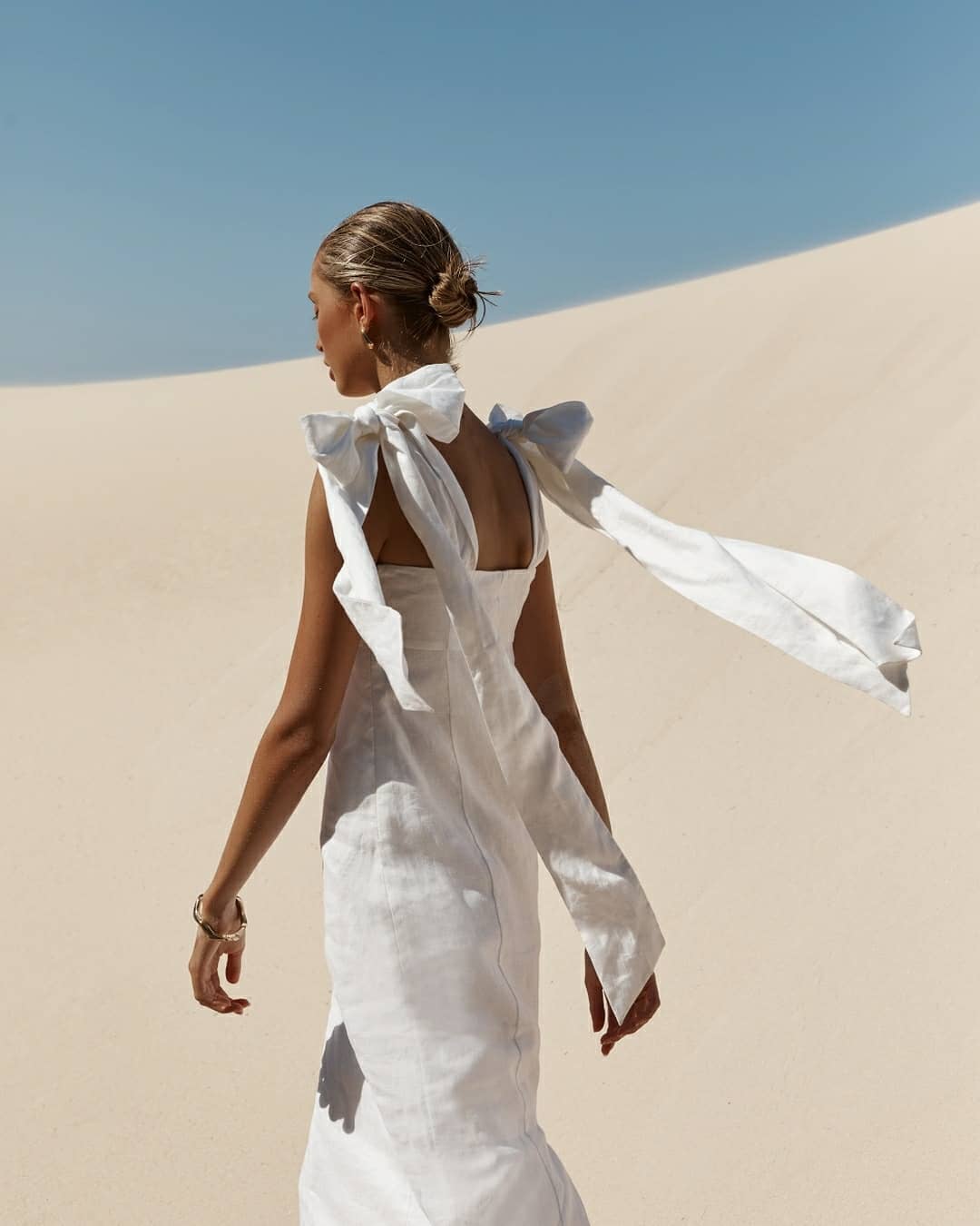 Back view of a white linen midi dress with long tie shoulder bows