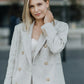  Woman wearing a beige double-breasted linen blazer with matching wide-leg linen trousers outdoors