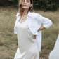 Woman outdoors wearing an ivory silk slip dress layered with an open white shirt
