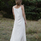 Person wearing a ivory dress standing in a natural setting with greenery.